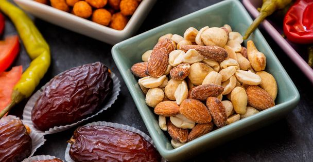 Mandelnüsse, Erdnüsse, Gewürznüsse, Paprika, Tong Da Tong in einer kleinen Tasse auf einem schönen Steintablett auf dem Tisch - Foto, Bild