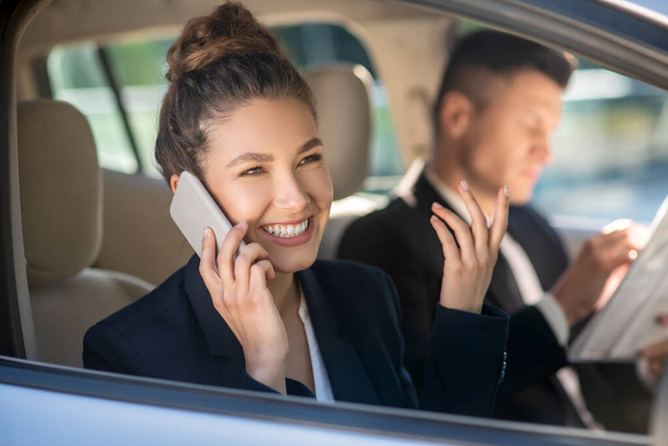 Successful smiling woman talking on a smartphone in a car - Photo, Image