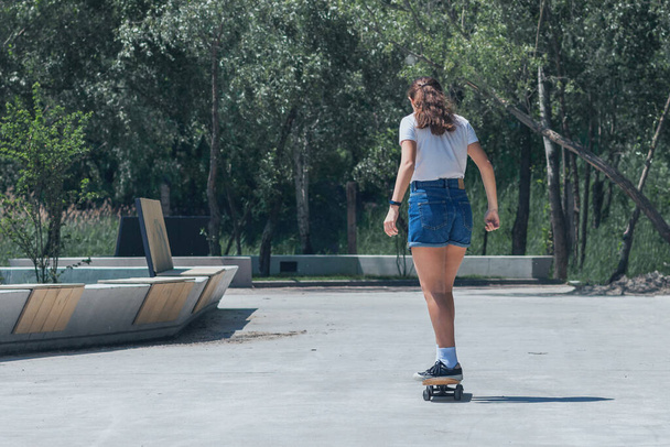 Teen girl skateboarding in the park. In sunny weather, on a hot summer day.  - Photo, Image