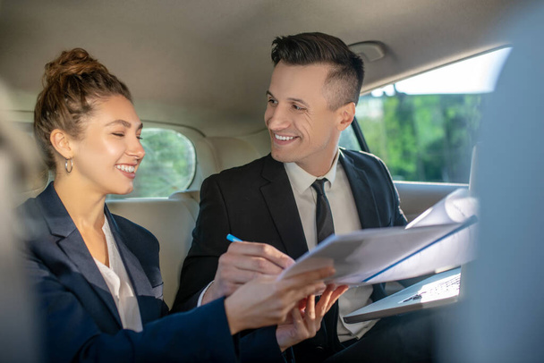 Happy man and woman signing document in car - Foto, Bild