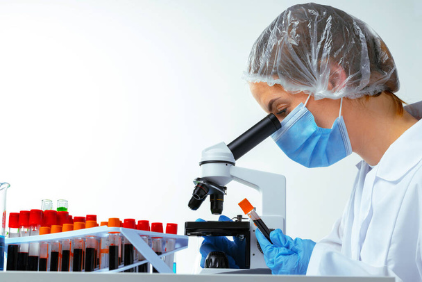 Woman scientist looking through a microscope in laboratory - Foto, immagini