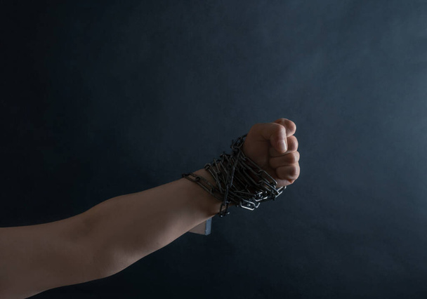 Puño de Mano están encadenados en cadenas sobre el fondo negro, concepto de Lucha y Libertad
. - Foto, imagen