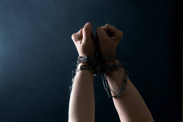Punhos de mãos estão acorrentados em cadeia no fundo preto, conceito de luta e liberdade
. - Foto, Imagem