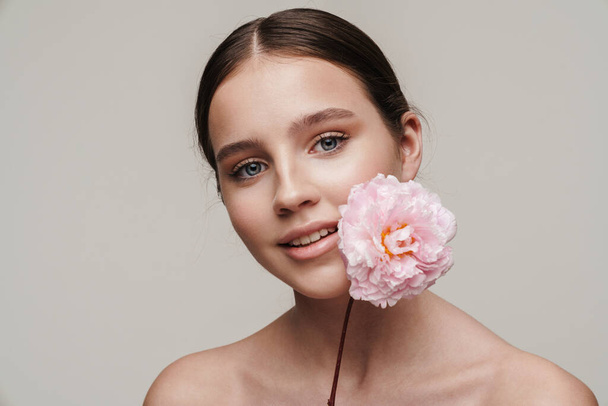 Image of pleased nice shirtless woman smiling while posing with pink peony isolated over grey background - Zdjęcie, obraz