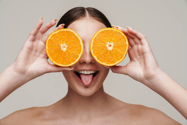 Image of cheerful nice shirtless woman smiling while making fun with orange isolated over grey background - Fotografie, Obrázek