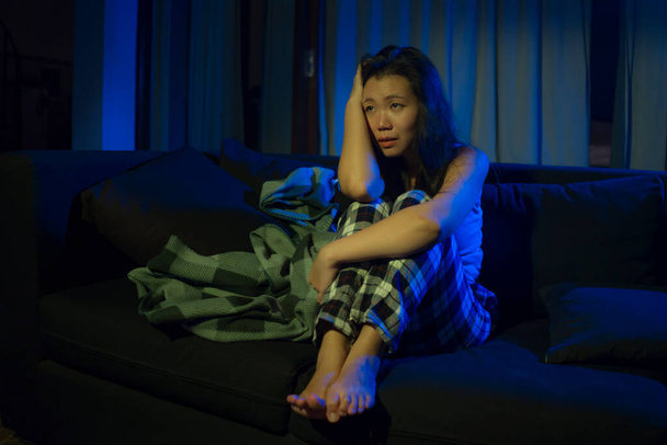dramatic home lifestyle portrait of young beautiful sad and depressed Asian Japanese woman in pain at living room sofa couch crying overwhelmed and desperate suffering depression and anxiety - Zdjęcie, obraz
