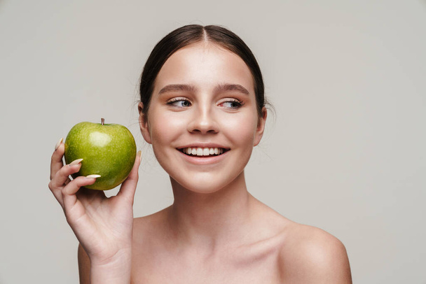 Image of beautiful laughing shirtless woman posing with green apple isolated over grey background - Foto, Imagem
