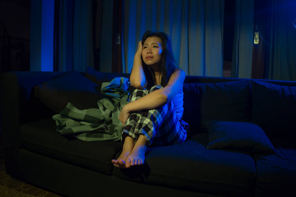 dramatic home lifestyle portrait of young beautiful sad and depressed Asian Korean woman lying in pain at living room sofa couch broken heart suffering depression and anxiety - 写真・画像