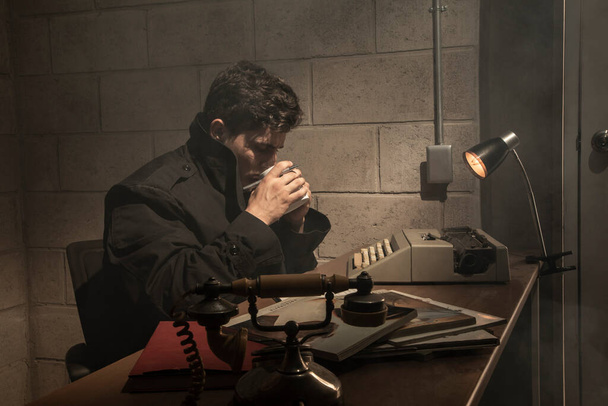 Dark and dramatic scene in a detective's office. heavy smoke. Detective working in a desk - Photo, Image