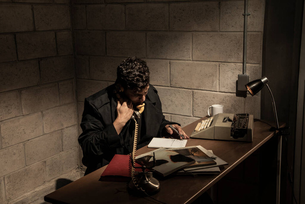 Scena buia e drammatica nell'ufficio di un detective. fumo intenso. Detective che lavora in una scrivania - Foto, immagini