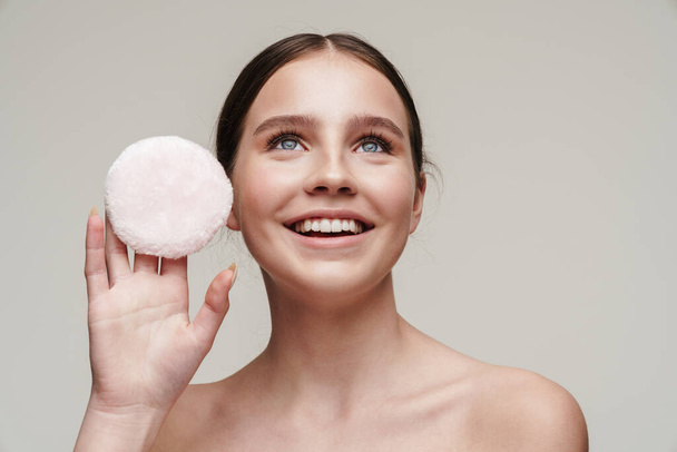 Image of pleased young shirtless woman showing makeup pad and smiling isolated over grey background - Photo, image