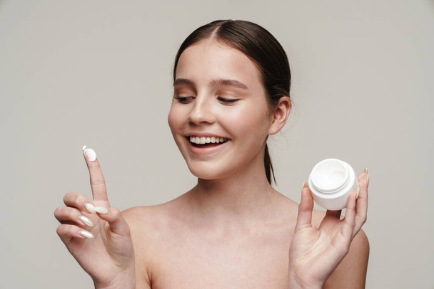 Image of pleased young shirtless woman showing face cream and smiling isolated over grey background - Fotoğraf, Görsel