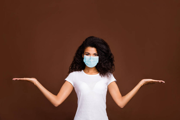 Portrait of her she attractive wavy-haired girl wearing gauze safety mask holding on palms copy space choose choice anti cov ncov infection isolated over dark brown color background - Foto, afbeelding