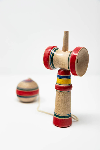 Оригинальная Кендама. Древняя, традиционная, деревянная японская игрушка для детей. Имеет три чашки и шип, который помещается в отверстие в мяче. Изолированный на белом фоне
. - Фото, изображение
