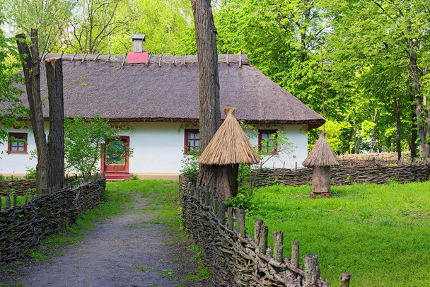 Malerische Landschaft Ansicht der alten Lehmhaus des Imkers. Im Garten stehen ein paar alte Bienenstöcke. Konzept der historischen Gebäude der alten Ukraine. - Foto, Bild