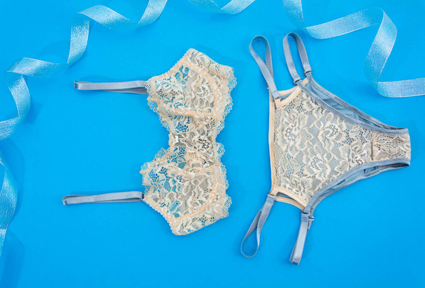 On a blue background, womens underwear is beige with lace beads - Фото, изображение