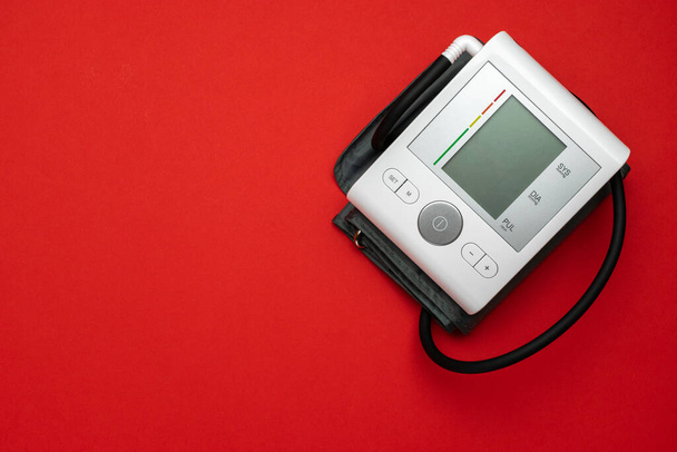 Sphygmomanometerコンセプト。赤い背景に隔離された医師の血圧をチェックするための健康モニター。医療用水腫からの患者のテスト高血圧計.フラットレイアウト、トップビュー、コピースペース - 写真・画像