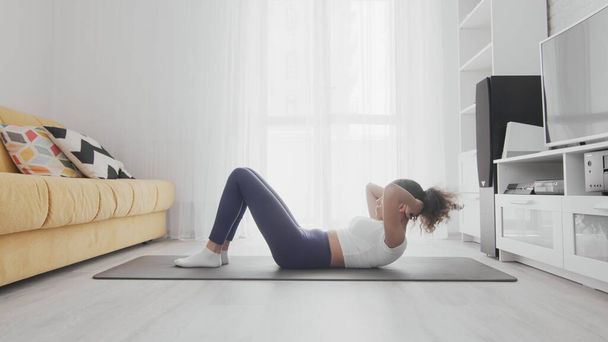 Szczupła, sportowa Afroamerykanka ćwicząca jogę na macie. kobieta dziewczyna robi mięśnie brzucha ćwiczenia w domu - Zdjęcie, obraz