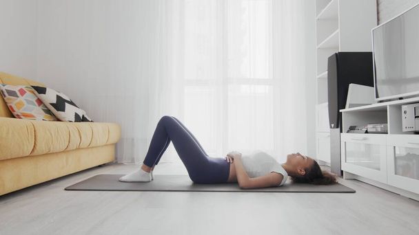 Zayıf, Afro-Amerikan kadın minderde yoga yapıyor. Kadın eğitimden sonra dinleniyor. - Fotoğraf, Görsel
