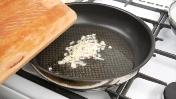 Ένας άνθρωπος τηγανίζει σκόρδο σε ένα τηγάνι και τον ενοχλεί με μια ξύλινη κουτάλα, κοντινό πλάνο - Πλάνα, βίντεο