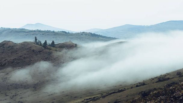 foggy morning in mountain valley, rock ridge on horizon in clouds and haze - Fotó, kép