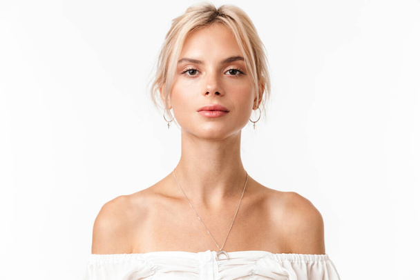 Image of beautiful blonde woman in earrings posing and looking at camera isolated over white background - Zdjęcie, obraz