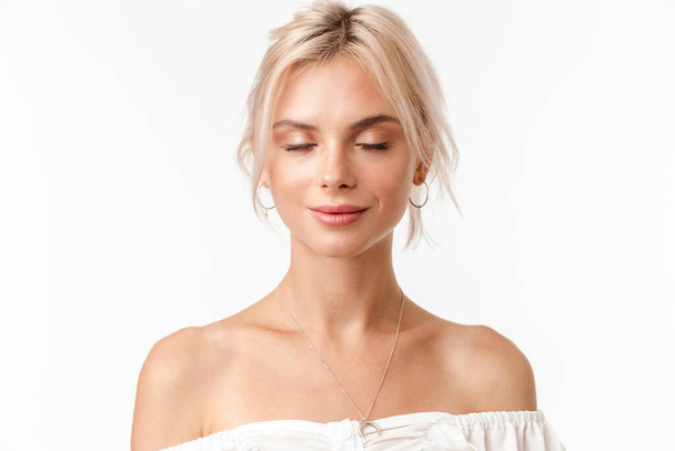 Image of calm blonde woman in earrings posing with eyes closed isolated over white background - Foto, imagen