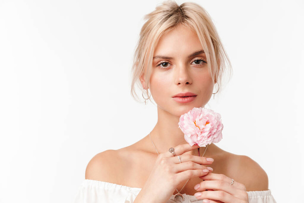 Imagem da bela mulher sedutora em brincos posando com flor na câmera isolada sobre fundo branco
 - Foto, Imagem