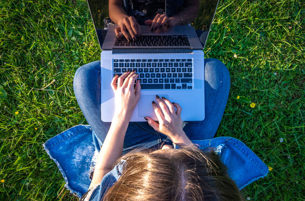 Dolgozz a laptopon. Diáknő számítógéppel, táblagép a nyári természetparkban. A lány kint üzletel az online technológiával. Elektronikus eszközök távoktatási koncepciója - Fotó, kép