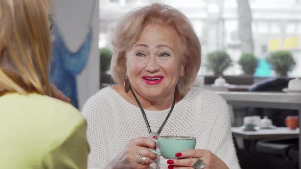 Bella donna anziana che ride parlando con sua figlia davanti a una tazza di tè - Filmati, video