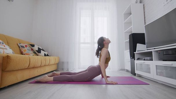 Portret pięknej szczupłej, wysportowanej kobiety ćwiczącej jogę na macie. Kobieta w stroju aktywnym uprawiająca jogę - High Cobra - Zdjęcie, obraz