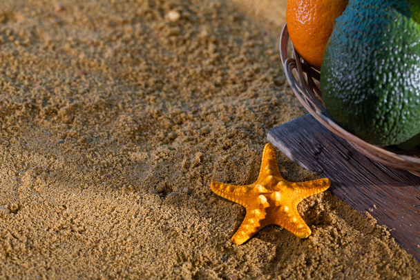 Ripe southern fruits lie in the basket. Sea shore of a sandy beach. - Foto, Imagem