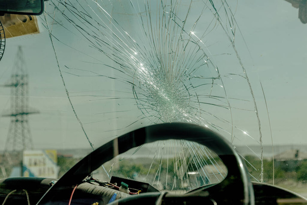Broken car windshield. Web of radial cracks, crack on triple windshield. Broken windshield car, damaged glass with traces of an oncoming stone on road or trace of downed pedestrian or animal on road - Photo, Image