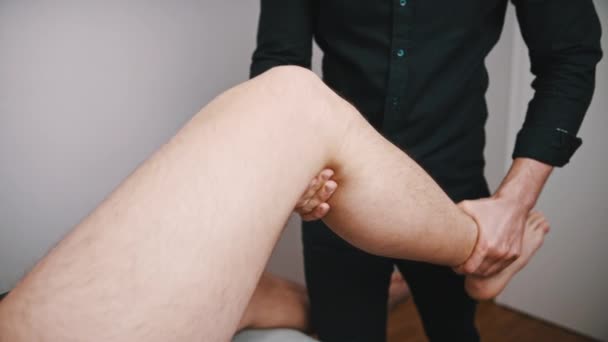 Młody człowiek bada kolano. Elastyczność kolana fizjoterapii - Materiał filmowy, wideo