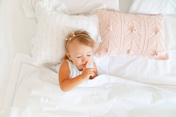 little girl sleeping in bed in bedroom with crown. Princess birthday party.  - Fotó, kép