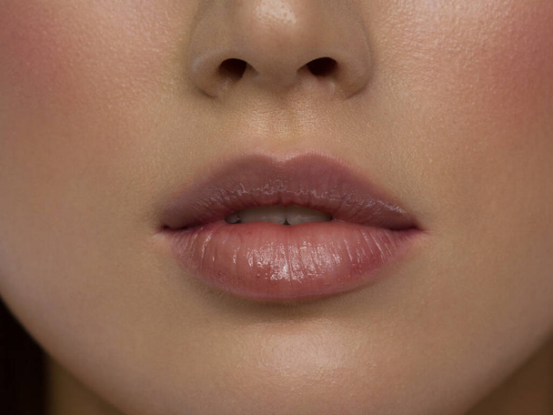 Sexual full lips. Natural gloss of lips and woman's skin. The mouth is closed. Increase in lips, cosmetology. Pink lips and long neck. Gentle pure skin and wavy blonde hair. - Фото, зображення