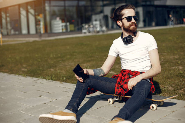 Stylish guy with skate in a summer city - Zdjęcie, obraz
