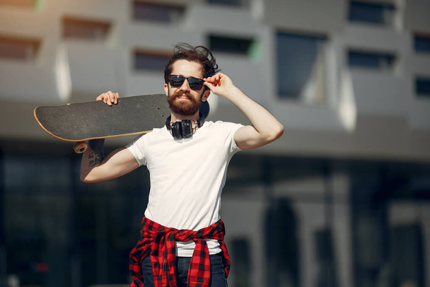 Stylish guy with skate in a summer city - Zdjęcie, obraz