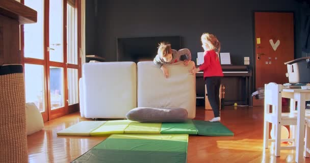 Two children playing together at home. Brother and sister play indoors. Front view medium shot. Kids playing in living room together. Slow motion - Materiał filmowy, wideo