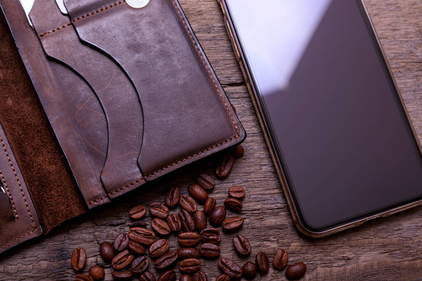 Still life photography of brown leather wallet, coffee beans, mobil phone and rope on vintage wooden background. Men casual concept, vintage and retro style. - Valokuva, kuva