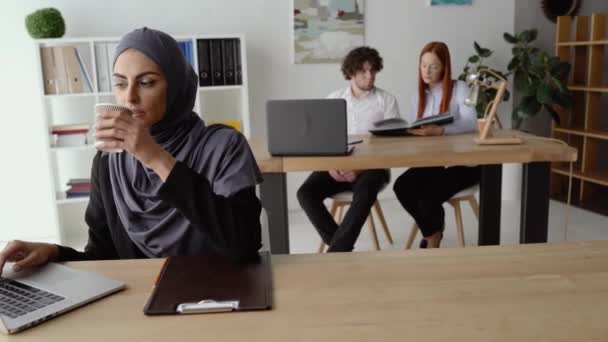 Thoughtful Arab woman drinking coffee and working on a laptop - Video, Çekim