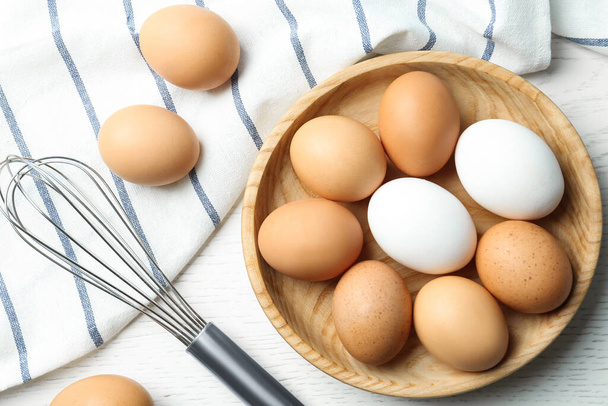 Chicken eggs and whisk on white wooden table, flat lay - Fotoğraf, Görsel