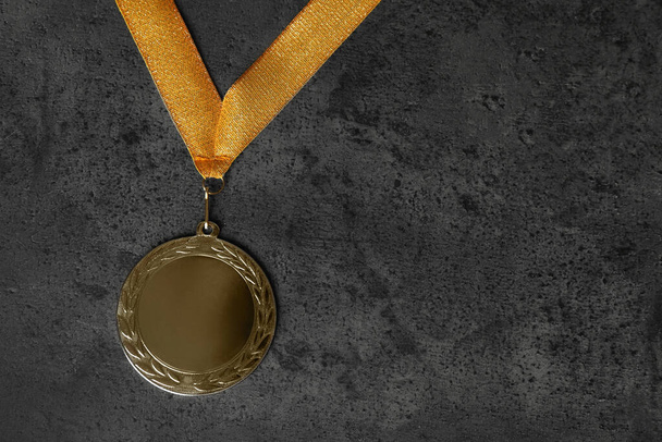 Gouden medaille op grijze stenen achtergrond, bovenaanzicht. Ruimte voor ontwerp - Foto, afbeelding
