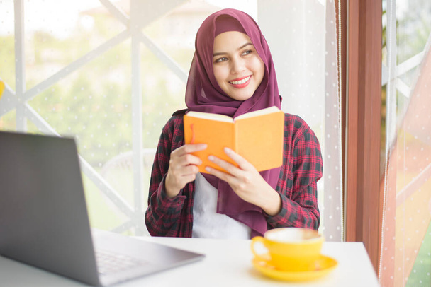 Muslim woman with hijab is working with laptop computer in coffee shop - Фото, зображення