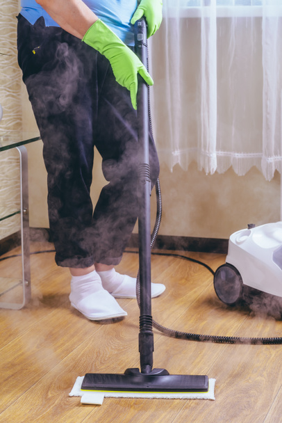 La mujer lava el suelo de la habitación con un limpiador de vapor blanco, un vapor húmedo de alta presión. Limpieza del apartamento. matar microbios
 - Foto, Imagen