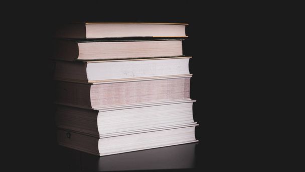 High messy stack of books on a black background with space for text message. - Photo, Image