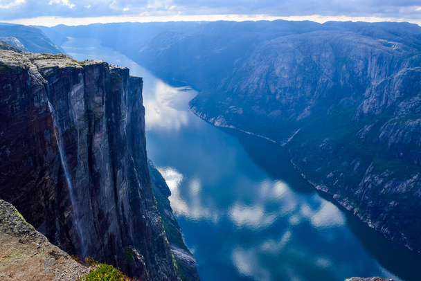 Wonderful mountain landscape of Lysefjorden with clouds reflected in blue water. View from Kjerag plateau, where not far at an altitude of 984 meters stuck between two rocks of Kjeragbolten. Norway. - Fotografie, Obrázek