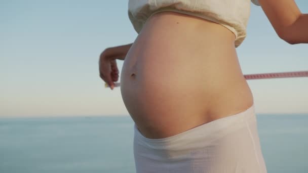 Young female measuring how big her during pregnancy belly still is. - Footage, Video