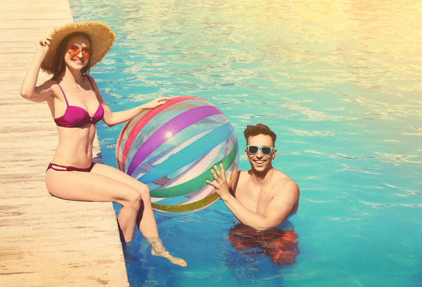 Happy young couple with inflatable ball at swimming pool - Foto, afbeelding