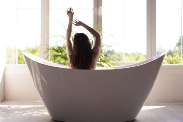 An Attractive girl relaxing in bath on light background. Blurred photo - Photo, Image